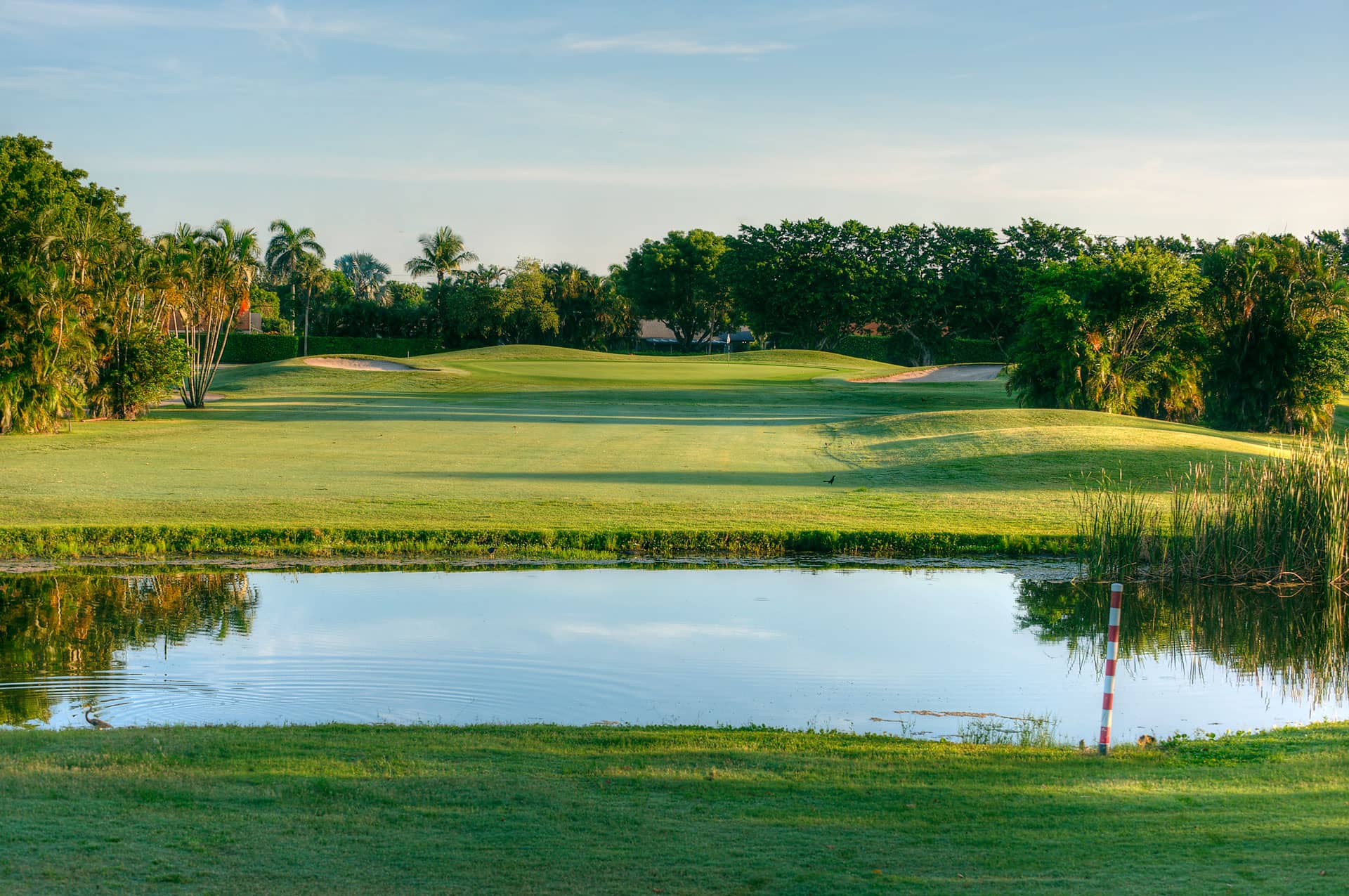 Water separating the tee box and fairway with green in the distance.